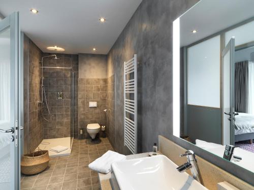 a bathroom with a sink and a shower and a toilet at Hôtel Beau Site Talloires B SPA in Talloires