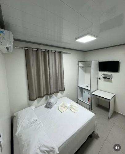 a bedroom with a white bed and a television at Hotel King Palace - Hotel Irituia in Irituia