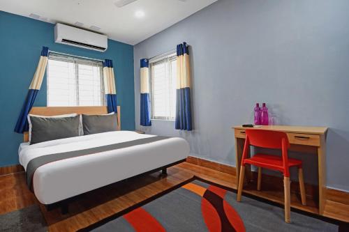 a bedroom with a bed and a desk and a red chair at Super Collection O Sayhallo Hillside Magnum in Bhubaneshwar