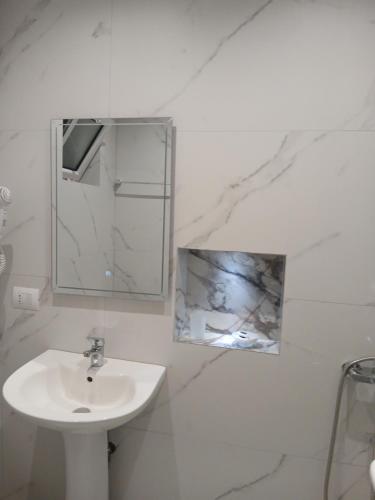 une salle de bain blanche avec un lavabo et un miroir dans l'établissement Sela Apartaments, à Ksamil