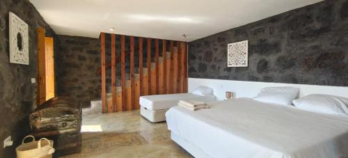 a bedroom with a large white bed and a chair at Bruma do Pico House in Lajes do Pico