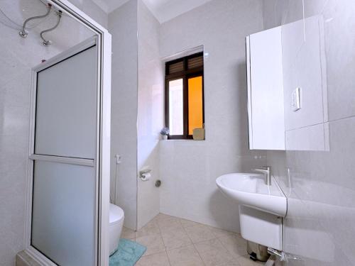 a white bathroom with a sink and a toilet at 3-bedroom Spacious Munyonyo Home in Kampala