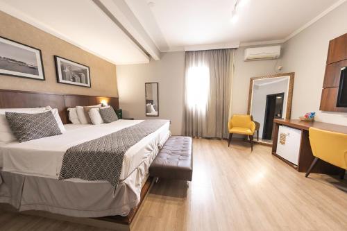 a hotel room with a bed and a yellow chair at Class Hotel Varginha in Varginha