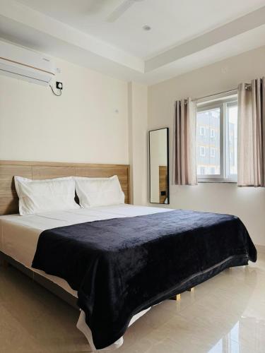 Un dormitorio con una cama grande con una manta azul. en Zyra Stays Hitech City, en Hyderabad