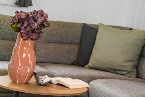 a vase with flowers on a coffee table next to a couch at C11593-Hemmet-Bork-Hytteby-98 in Hemmet