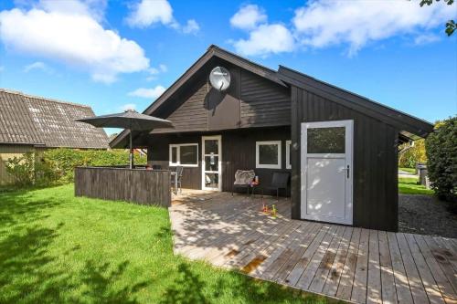a black house with a patio and an umbrella at C11593-Hemmet-Bork-Hytteby-98 in Hemmet