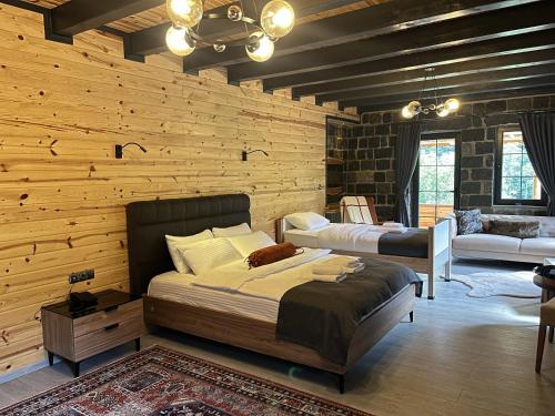 a bedroom with wooden walls and a bed and a couch at Hemşin Ata Konağım in Çamlıhemşin