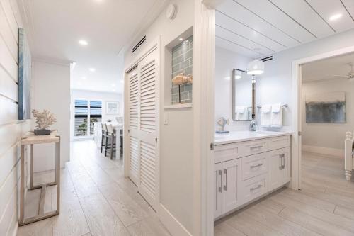 a white bathroom with a sink and a mirror at Lovely Marco Island Condo with Private Bay View in Marco Island