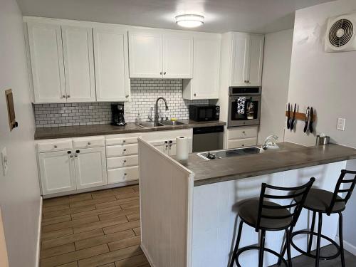 a kitchen with white cabinets and two bar stools at Sunny Condo Steps from Sand in San Diego