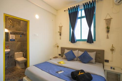 a bedroom with a bed with blue pillows and a window at Shalom Backpackers Anjuna Goa in Anjuna