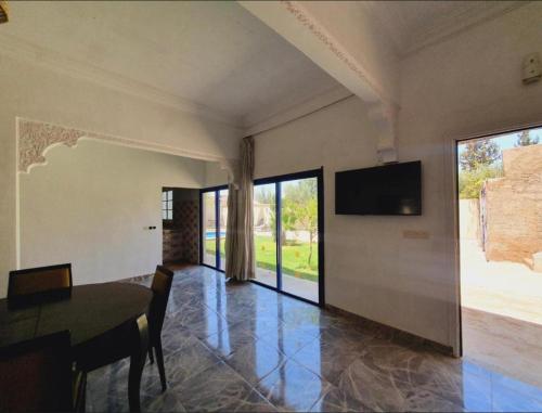 a dining room with a table and a television on a wall at Maison Royale in Douar bel Rhanodour