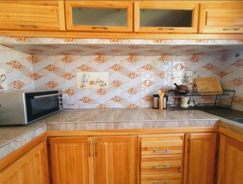 a kitchen with wooden cabinets and a microwave at Maison Royale in Douar bel Rhanodour