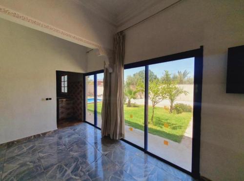 an empty room with a large glass door to a yard at Maison Royale in Douar bel Rhanodour
