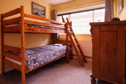 a bedroom with two bunk beds and a window at Rhianfa Manorbier in Manorbier