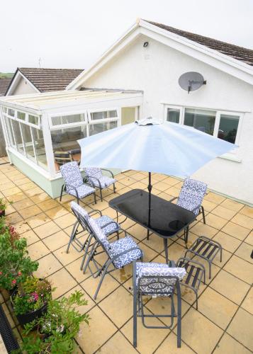 a patio with a table and chairs and an umbrella at Rhianfa Manorbier in Manorbier