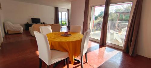 a dining room with a table and white chairs at Bruma do Pico House in Lajes do Pico