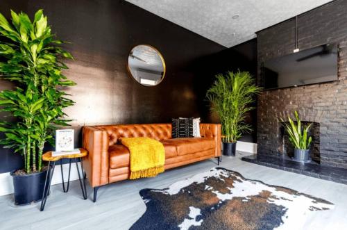 a living room with a leather couch and plants at Jungle House Boutique Residences - Downtown Columbus & Short North in Columbus