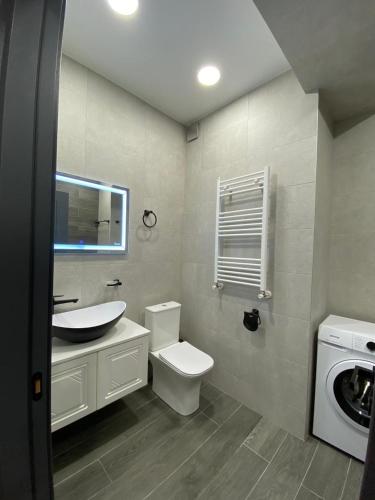 a bathroom with a toilet and a sink and a washing machine at Aparthotel Hilton Blox in Tbilisi City