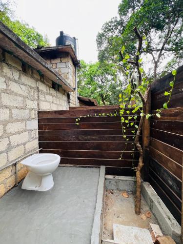 a toilet sitting outside of a building with a fence at Hakuna Matata Hostel in Sigiriya