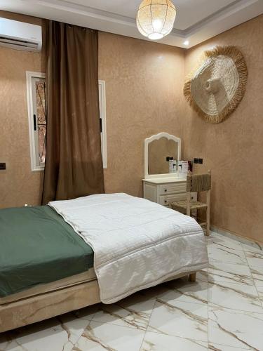 a bedroom with a bed and a table and a mirror at Chambre d'hôtes dans luxueuse villa avec piscine in Had Abdallah Rhiat