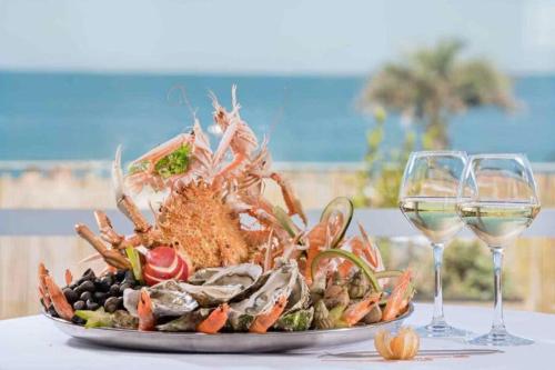 a plate of seafood with two glasses of wine at Charmante petite maison de ville à 20 minutes de la mer in Giberville