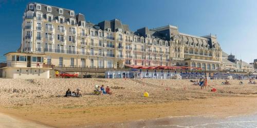 a large building on a beach with people on the sand at Charmante petite maison de ville à 20 minutes de la mer in Giberville