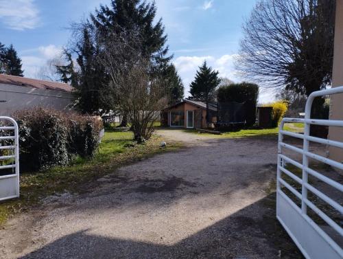 a driveway with a white fence in front of a house at House on the edge of the forest in Dolomieux