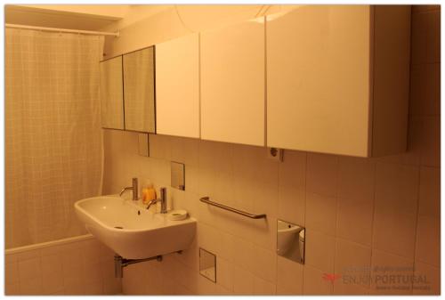 a white bathroom with a sink and a mirror at Feelings Aveiro Apartment in Aveiro