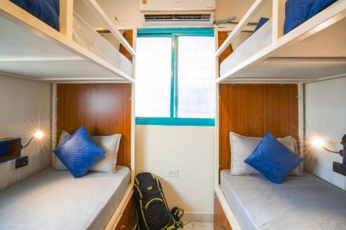 two bunk beds in a small room with blue pillows at Shalom Backpackers Anjuna Goa in Anjuna