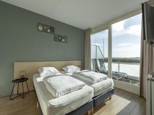two beds in a room with a large window at Apartment near Groote Keeten Beach in Groote Keeten