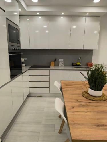 a kitchen with white cabinets and a wooden table at Me&You - Apartamento em Sesimbra - 5 minutos a pé da praia in Sesimbra