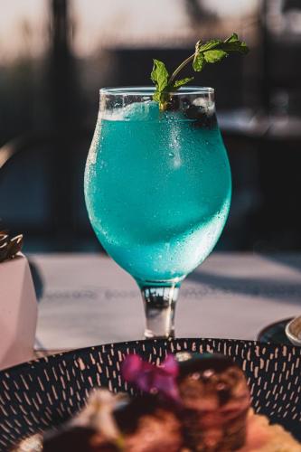 a blue drink in a glass sitting on a table at InHouse Glamping Hotel La Paz in La Paz