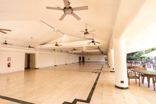 an empty room with tables and ceiling fans at Best Western Las Mercedes Airport in Managua