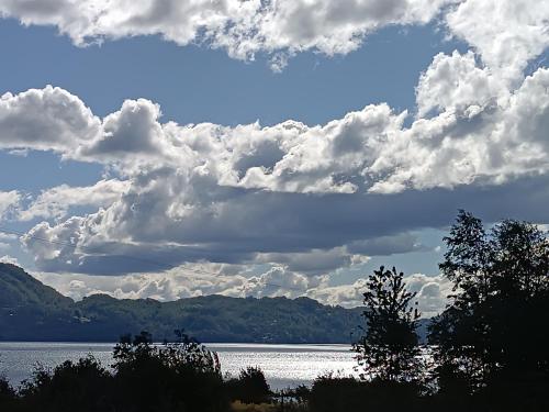 a view of a large body of water with clouds at Hostel Calafquen Adventure Coñaripe in Coñaripe