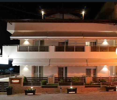 a large white building with lights on it at night at Filippos studios in Leptokaria