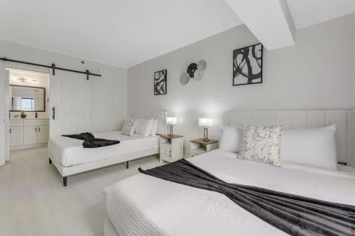 a white bedroom with two beds and two tables at Luxury Private Apt at Disney Area in Orlando