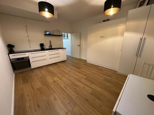a kitchen with white cabinets and a hard wood floor at Ferienwohnung MarLeo Landsberg am Lech in Landsberg am Lech