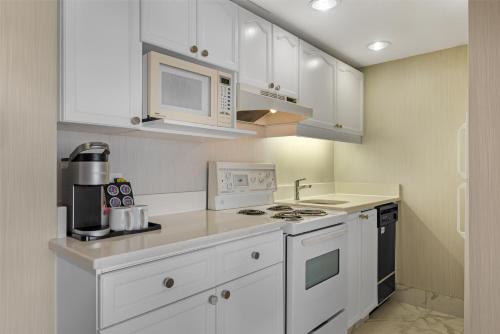 a kitchen with white cabinets and a stove and microwave at Best Western Plus Suites Downtown Calgary in Calgary