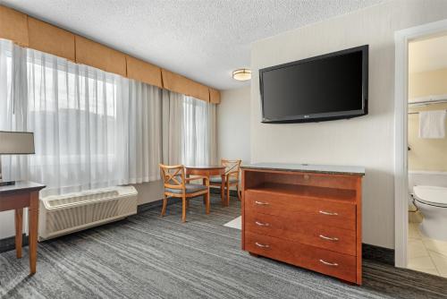 a hotel room with a bathroom with a toilet and a television at Best Western Plus Suites Downtown Calgary in Calgary