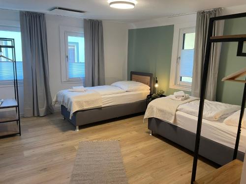 two beds in a room with two windows at CharmÖHR Homes in Öhringen