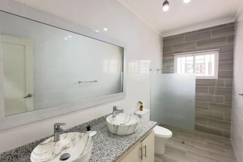 une salle de bain avec deux lavabos et un grand miroir dans l'établissement Elegante Casa Estrella Marina 117 Pool BBQ, à La Romana
