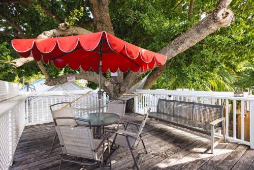 a table and chairs on a deck with a red umbrella at Traveler's Palm in Key West