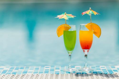two glasses of cocktails with orange slices and a swimming pool at Grand Palace Hotel & Resort Sylhet in Sylhet