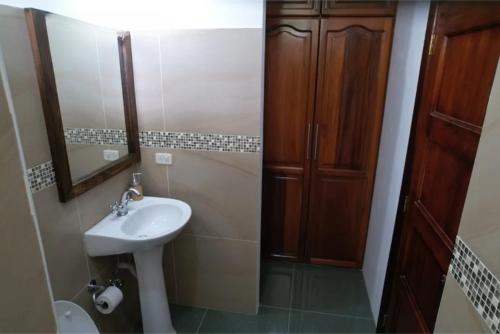 a bathroom with a sink and a wooden cabinet at Coastal Villa Retreat with Private Jacuzzi and Garage Near Isla de la Plata in Puerto López
