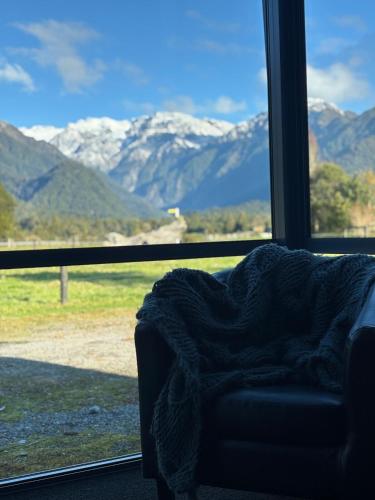 a blanket laying on a couch in front of a window at Glacier Barn House in Tatare