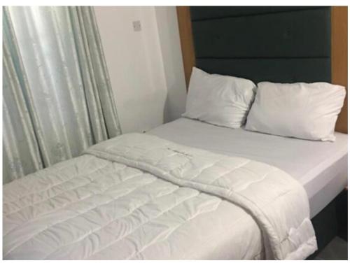 a bed with white sheets and pillows next to a window at Epe Hotels & Suites in Epe