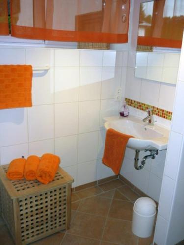 a bathroom with orange towels and a sink and a basket at Landhaus Almdorf in Sankt Johann in Tirol