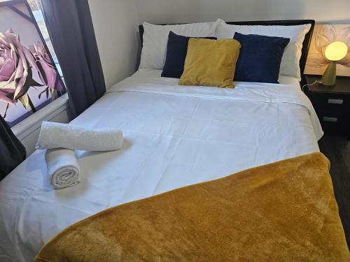 a large white bed with yellow and blue pillows at Ensuite Double Room with Private Kitchen Dudley in Dudley