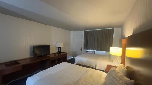 a hotel room with two beds and a flat screen tv at Super 8 by Wyndham San Jose Airport in San Jose