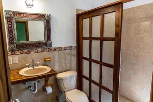 ein Badezimmer mit Toilette, Waschbecken und Spiegel in der Unterkunft Cabaña Libélula para parejas in Mascota